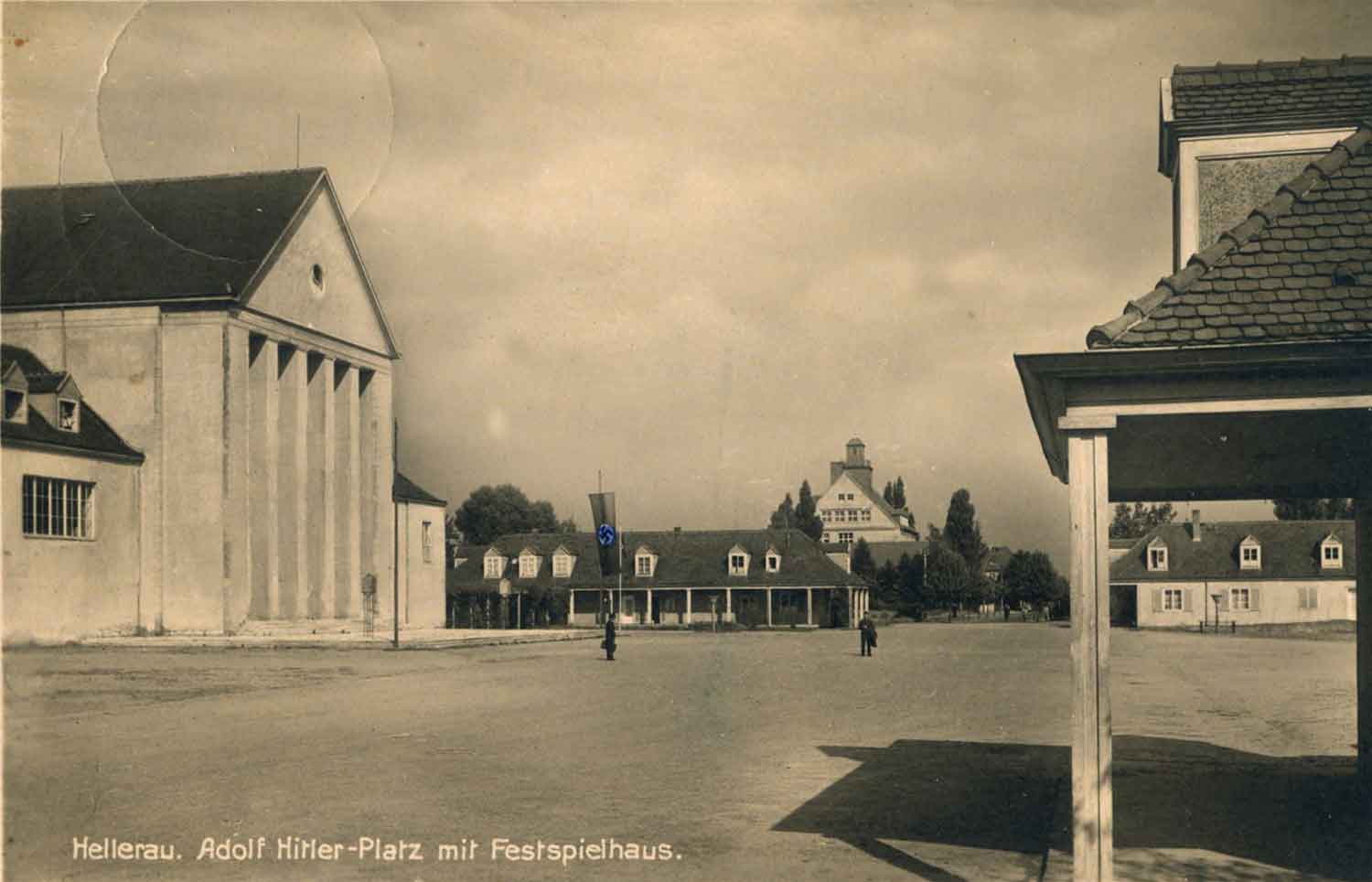 Foto, schwarz-weiß: Links das Festspielhaus, im Hintergrund ein Pensionshaus, davor die Fläche des Festspielhausgeländes.