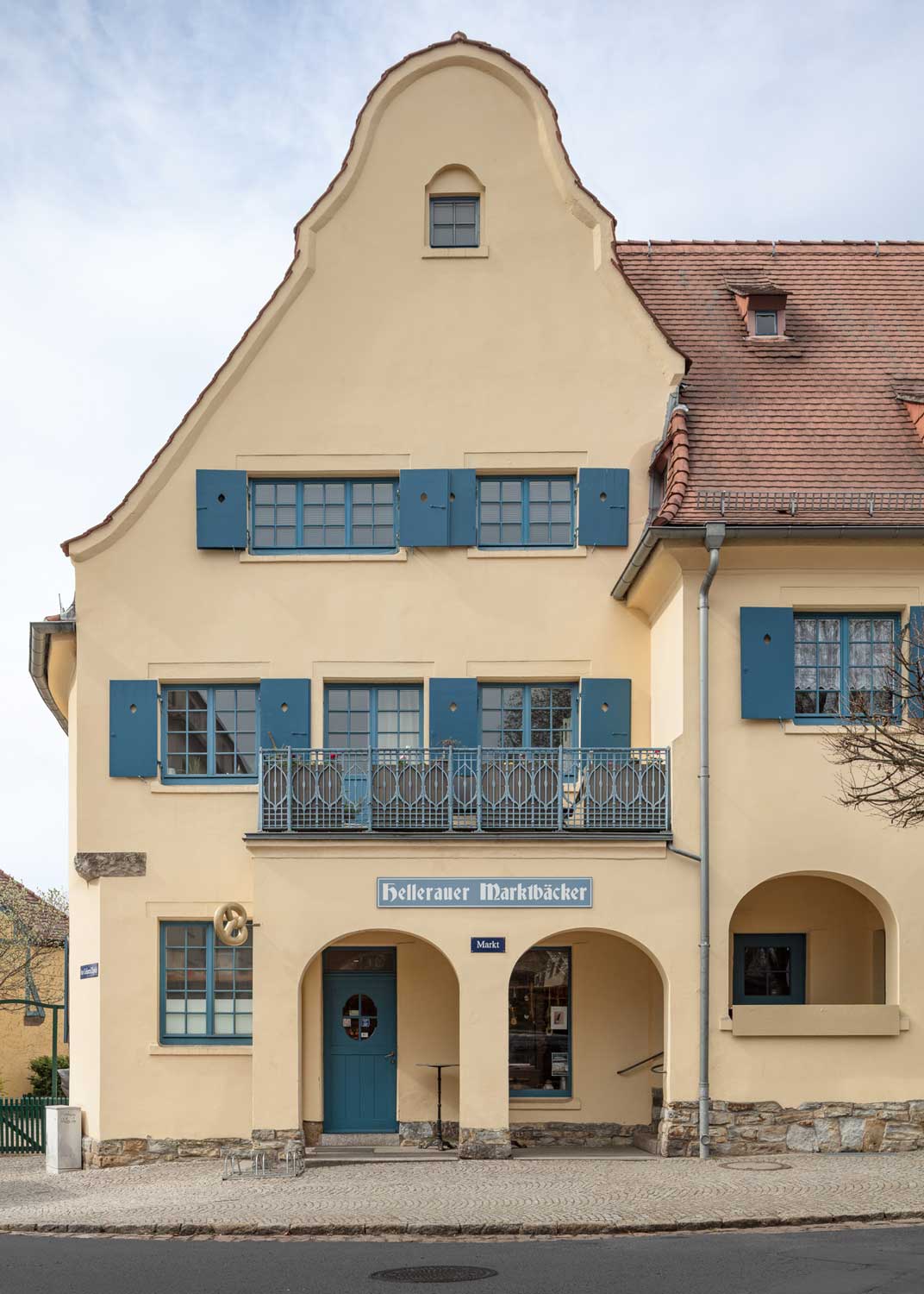 Foto, farbig: Haus mit sandfarbener Fassade und Ziegeldach.