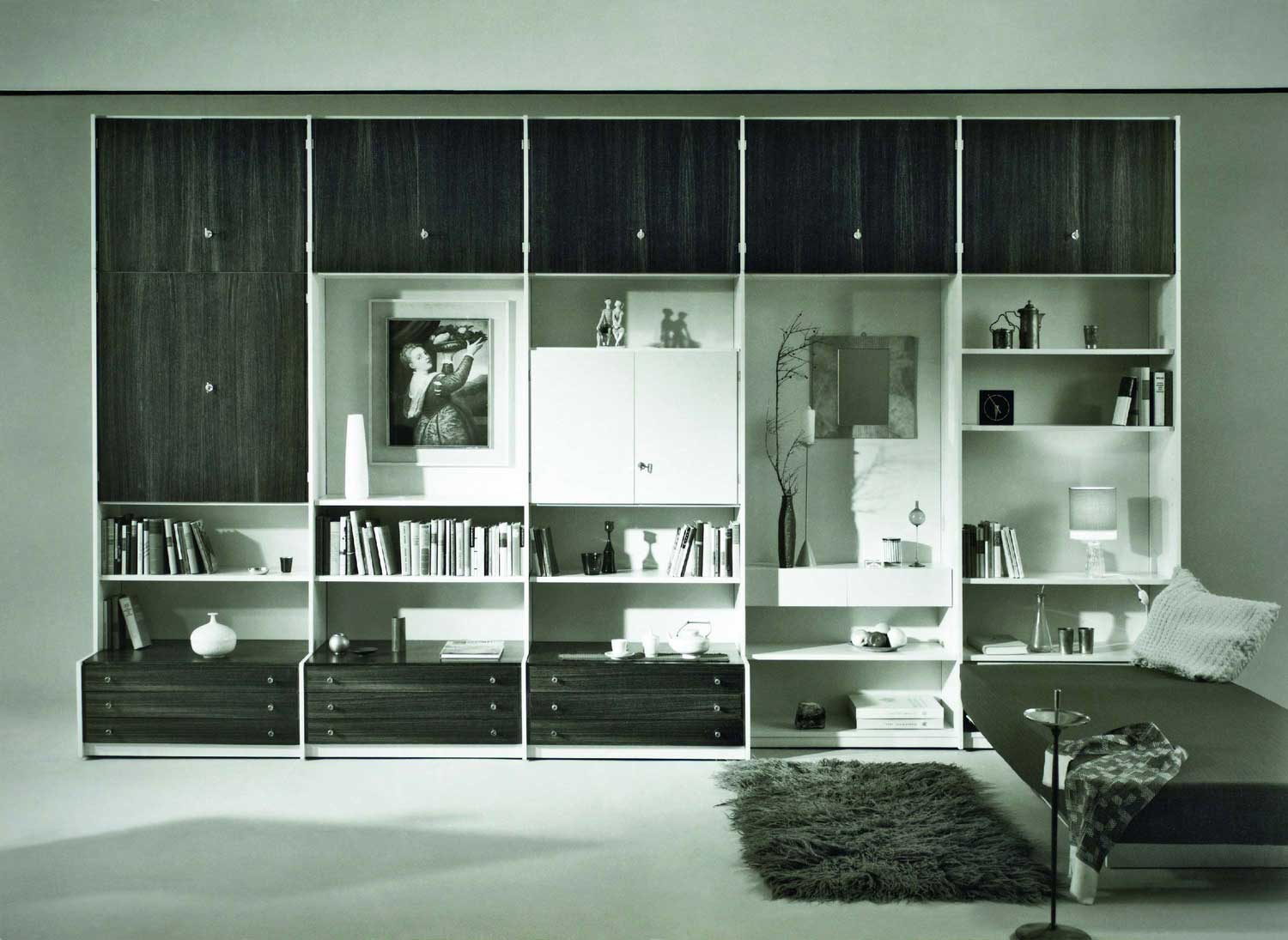 Foto, schwarz-weiß: Schrankwand aus fünf Typen-Elementen nebeneinander mit schwarzen Türen und offenen Regalreihen.